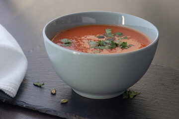 Bowl of red tomato cream soup on wooden table