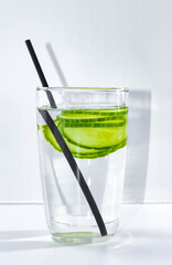 Detox water with a sliced cucumber in a glass with a straw for drinking. The concept of losing weight and cleansing the body. vertical frame.