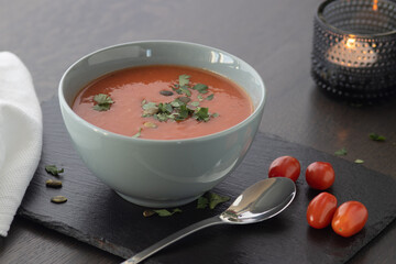 Bowl of red tomato cream soup on wooden table