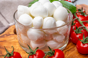 Italian tricolore, small balls of fresh white soft Italian mozzarella cheese, ripe red cherry tomatoes and fresh green basil herb, ready for making caprese salad