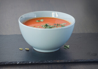 Bowl of red tomato cream soup on wooden table