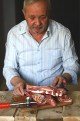 A male chef cuts raw pork ribs. Preparing pork ribs for barbecuing or grilling. Cooking and cutting pork.