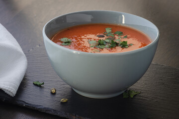 Bowl of red tomato cream soup on wooden table