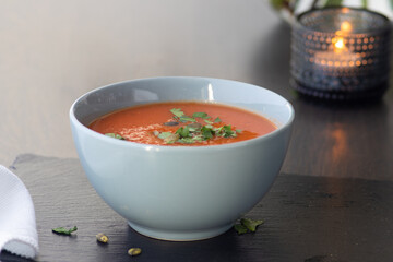 Bowl of red tomato cream soup on wooden table
