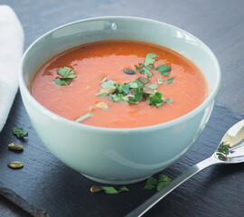 Bowl of red tomato cream soup on wooden table