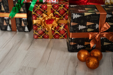 Several orange Christmas balls are lying on the floor and next to them colorful gift boxes.