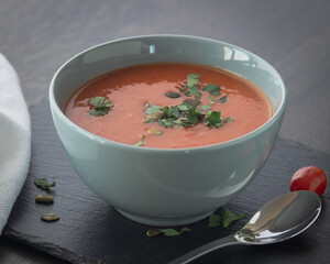 Bowl of red tomato cream soup on wooden table
