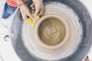 Female potter making clay pottery on a spin wheel.