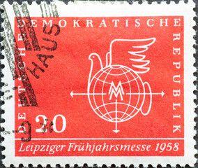 GERMANY, DDR - CIRCA 1958 : a postage stamp from Germany, GDR showing a globe, dove of peace, trade fair mark. Leipzig Spring Fair 1958. red