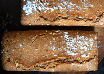Homemade freshly baked whole grain rye bread with seeds on a black background