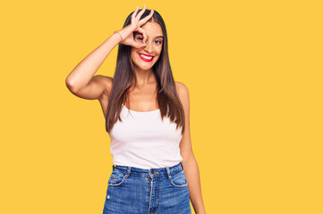Fototapeta premium Young hispanic woman wearing casual clothes smiling happy doing ok sign with hand on eye looking through fingers