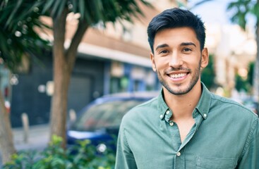 Young latin man smiling happy walking at the city.