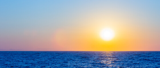 Fototapeta premium Orange sunset over sea. Bright sun over the sea horizon. Concept: vacation, relax, romantic