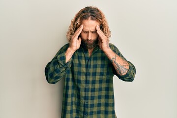 Handsome man with beard and long hair wearing casual clothes with hand on head for pain in head because stress. suffering migraine.