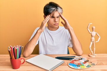 Young hispanic man artist sitting at the studio with hand on head, headache because stress. suffering migraine.