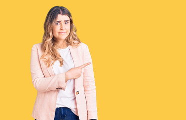 Young caucasian woman wearing business clothes pointing aside worried and nervous with forefinger,...