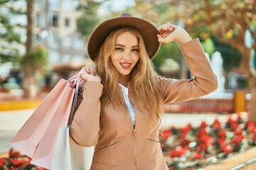 Young blonde girl shopping holding bags at the city.
