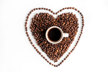 A coffee is a hug in a mug. A cup inside a heart made of coffee beans with a line of beans around it. Flat lay composition on a white background.