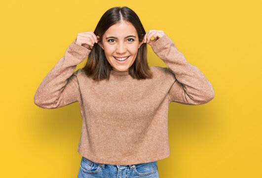 Young beautiful woman wearing casual clothes smiling pulling ears with fingers, funny gesture. audition problem