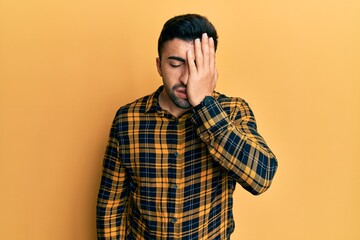 Young hispanic man wearing casual clothes yawning tired covering half face, eye and mouth with hand. face hurts in pain.