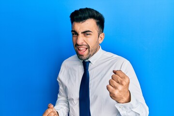 Young hispanic man wearing business clothes very happy and excited doing winner gesture with arms raised, smiling and screaming for success. celebration concept.