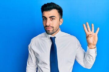 Young hispanic man wearing business clothes showing and pointing up with fingers number four while smiling confident and happy.