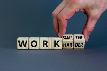 Work harder or smarter symbol. Businessman turns wooden cubes and changes words 'work harder' to 'work smarter'. Beautiful grey background, copy space. Business and work harder or smarter concept.