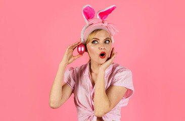 Surprised woman in bunny ears with pink eggs. Happy Easter. Hunting eggs. Amazed girl with colored egg. Spring holiday.