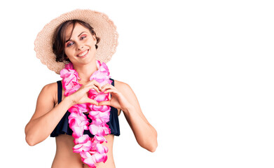 Beautiful young woman with short hair wearing bikini and hawaiian lei smiling in love showing heart symbol and shape with hands. romantic concept.