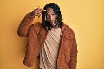 African american man with braids wearing brown retro jacket pointing unhappy to pimple on forehead,...