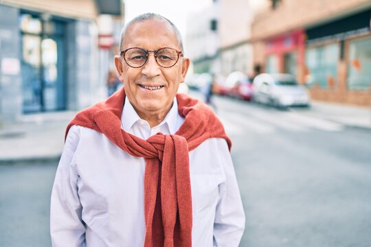 Senior man smiling happy wearing glasses walking at the city.