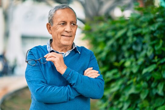 Senior grey-haired man with arms crossed smiling happy standing at the city.