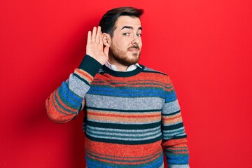 Handsome caucasian man with beard wearing elegant wool winter sweater smiling with hand over ear listening an hearing to rumor or gossip. deafness concept.