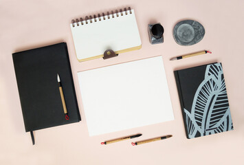 Blank sheet mockup, notepads and calligraphy brushes. Top view: Attributes for calligraphy. Flatley harmoniously laid out objects.