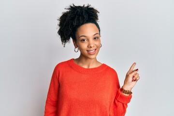 Young african american girl wearing casual clothes with a big smile on face, pointing with hand finger to the side looking at the camera.