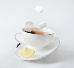 tea in a white cup with lemon, tea bag and sugar. balance and levitation