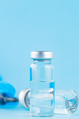 Vaccine, syringe and surgical glove. Two bottles of vaccine and syringe on a blue background. Vaccine and healthcare medical concept