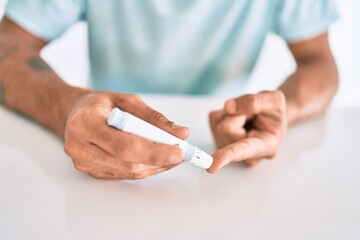 Fototapeta premium Young hispanic diabetic man measuring glucose level at home