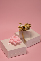 white gift boxes with gold and rose ribbon on pink background 