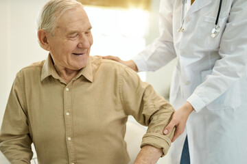 Obraz premium Mirthful elderly man being helped up by medical staff