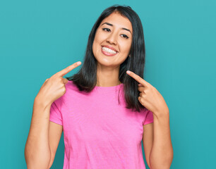 Beautiful asian young woman wearing casual pink t shirt smiling cheerful showing and pointing with fingers teeth and mouth. dental health concept.