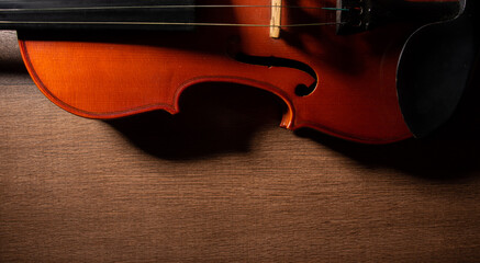 Fototapeta premium Violin, details of a beautiful violin on wooden surface and black background, low key selective focus portrait.
