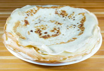 Ukrainian mlyntsi, closeup stack of thin pancakes on a plate, fundamental dish of Ukrainian cuisine
