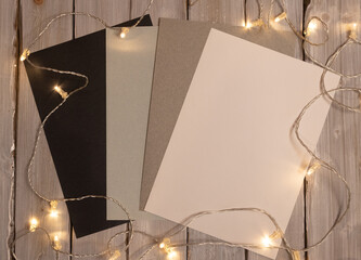 empty blank, sheets and notebooks with lights on wooden background
