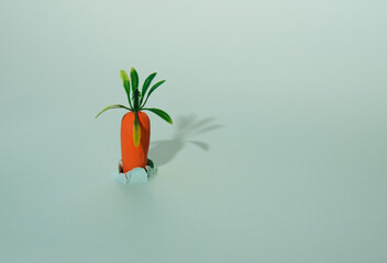 A carrot grows out of torn paper and casts a shadow on the background.