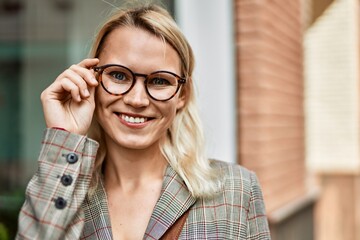 Young blonde businesswoman smiling happy standing at the city.