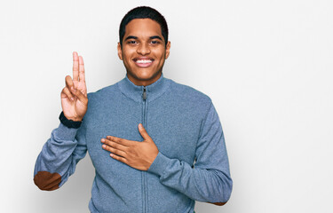 Young handsome hispanic man wearing casual sweatshirt smiling swearing with hand on chest and...