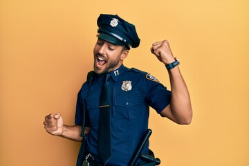 Handsome hispanic man wearing police uniform dancing happy and cheerful, smiling moving casual and confident listening to music