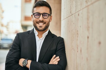 Young hispanic businessman with arms crossed smiling happy at the city.