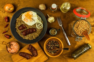 Lentils with sausage and chili. Grilled sausage and lentils with egg on a black plate. Legumes. Healthy food.